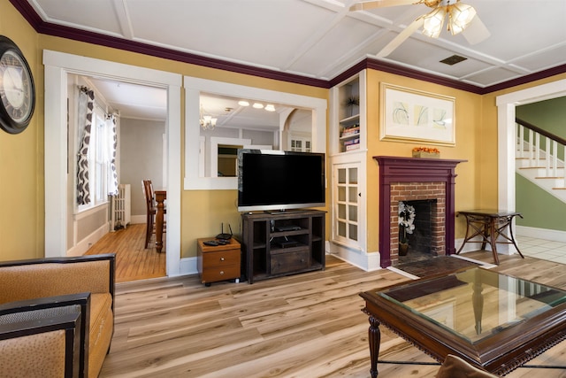 living room featuring wood finished floors, ceiling fan, stairs, baseboards, and crown molding