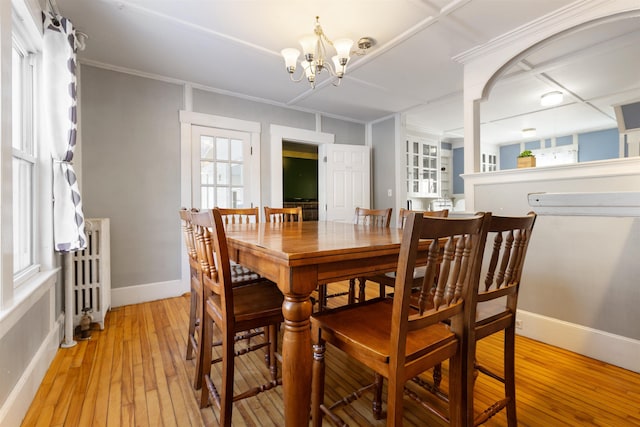 dining room featuring radiator heating unit, a chandelier, light wood-style floors, and baseboards