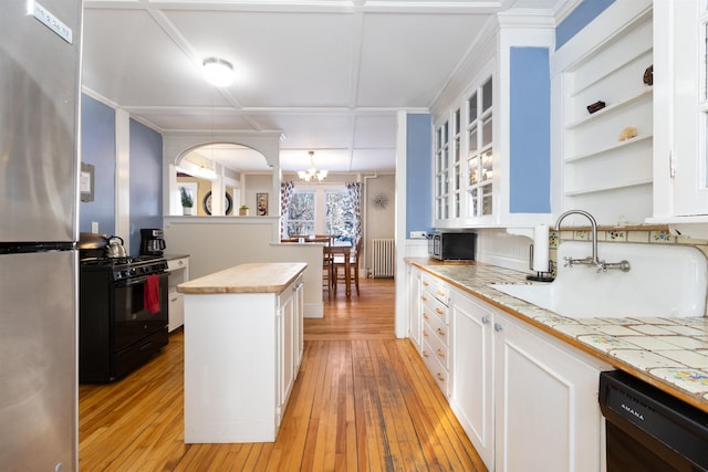 kitchen with black appliances, radiator, a sink, and light wood-style floors