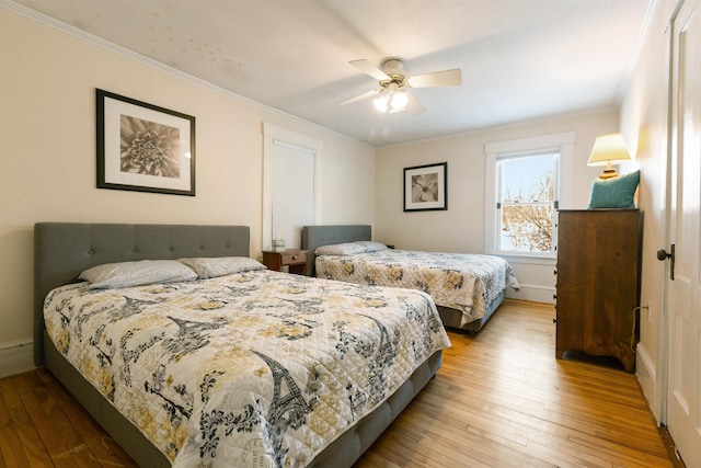 bedroom with hardwood / wood-style floors, crown molding, and a ceiling fan