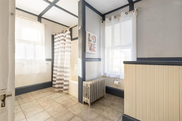 full bathroom featuring radiator heating unit, a wainscoted wall, shower / bath combo, and tile patterned floors