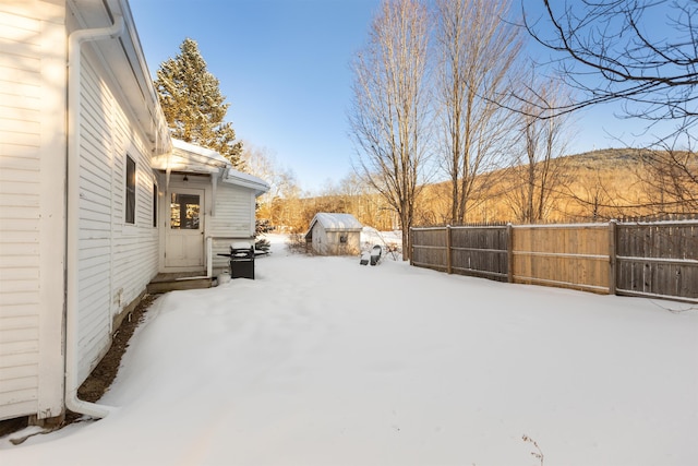 yard layered in snow featuring fence, an outdoor structure, and a storage unit