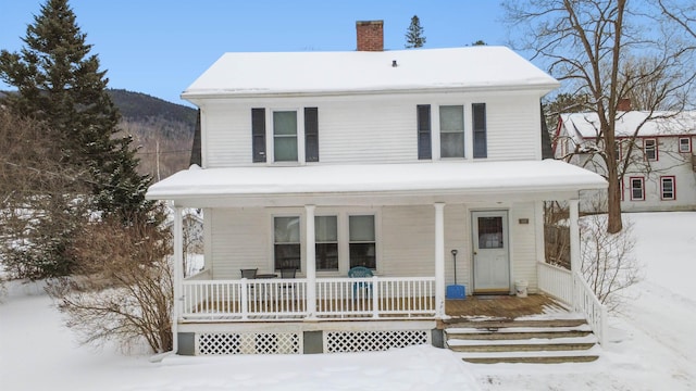 view of front of house featuring a porch, a chimney, and a mountain view