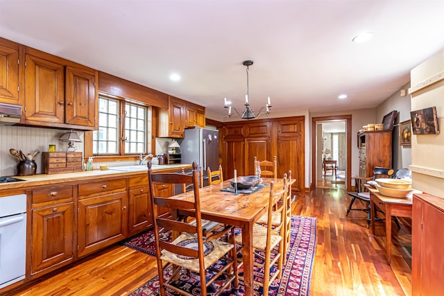 kitchen featuring white oven, light wood-type flooring, light countertops, freestanding refrigerator, and brown cabinetry