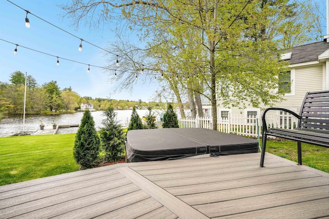 deck with a water view, a hot tub, and a lawn