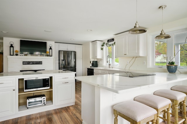 kitchen with stainless steel microwave, black electric stovetop, refrigerator with ice dispenser, plenty of natural light, and recessed lighting