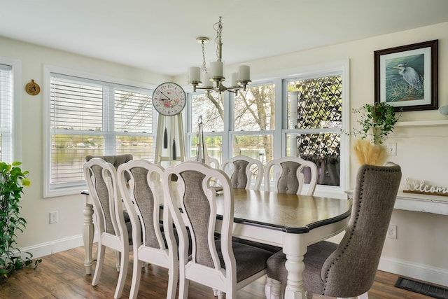 dining room featuring a chandelier, healthy amount of natural light, baseboards, and wood finished floors