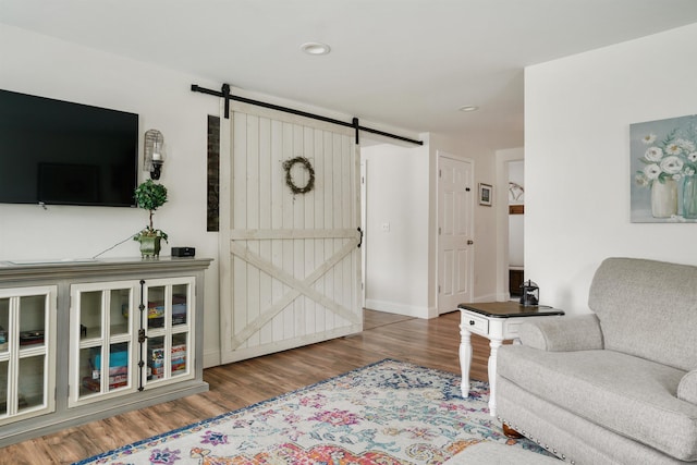 living room featuring a barn door, wood finished floors, recessed lighting, and baseboards