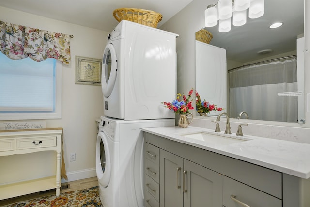 laundry area featuring stacked washer and clothes dryer, light wood-style floors, baseboards, and recessed lighting
