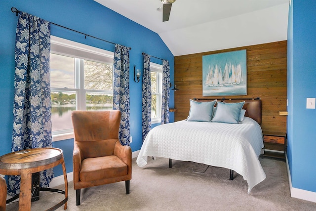 carpeted bedroom with lofted ceiling, wooden walls, ceiling fan, and baseboards