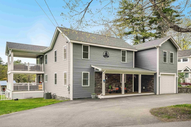 view of front of home with asphalt driveway, covered porch, central AC unit, and a garage