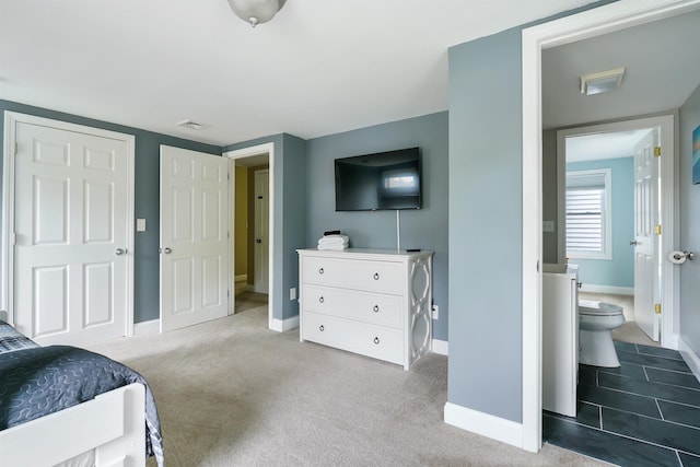 carpeted bedroom featuring baseboards and ensuite bathroom