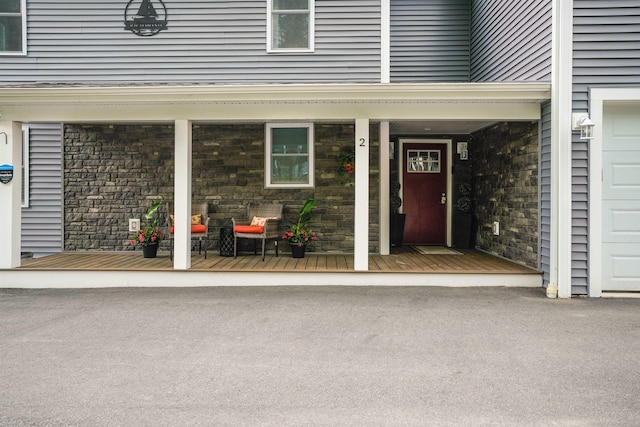 doorway to property with a porch and stone siding