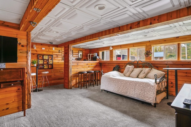 carpeted bedroom featuring wooden walls and an ornate ceiling