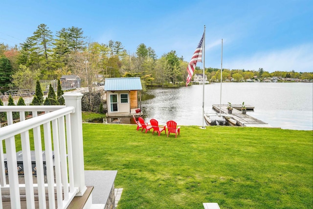 view of green lawn with a water view and a dock