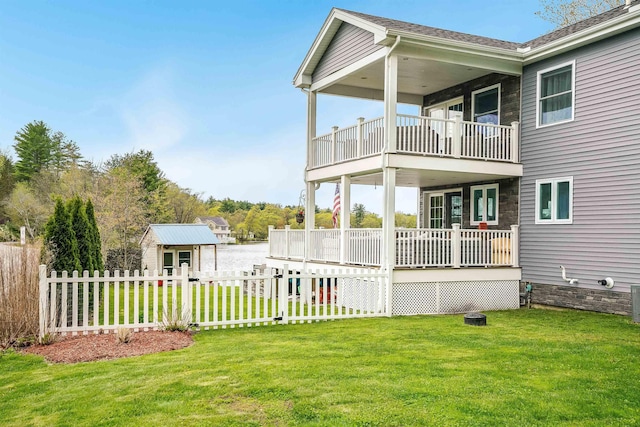 rear view of property with a balcony, an outbuilding, and a storage unit