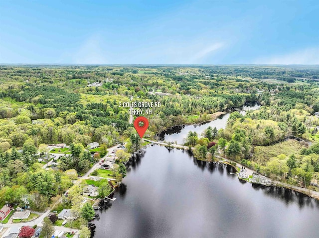 aerial view of property and surrounding area featuring a forest and a nearby body of water