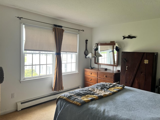 bedroom with a baseboard heating unit, multiple windows, carpet flooring, and a textured ceiling