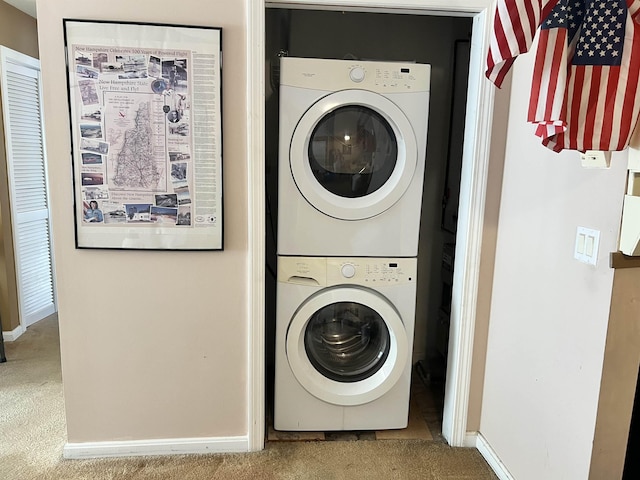 laundry area with stacked washer / drying machine, carpet, and baseboards