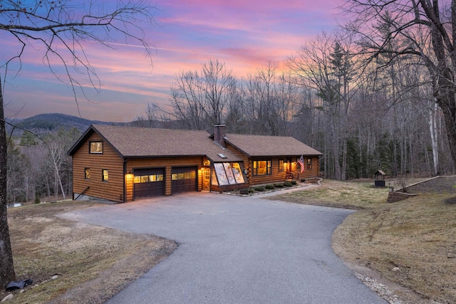 view of front of home with asphalt driveway, a chimney, an attached garage, and a mountain view