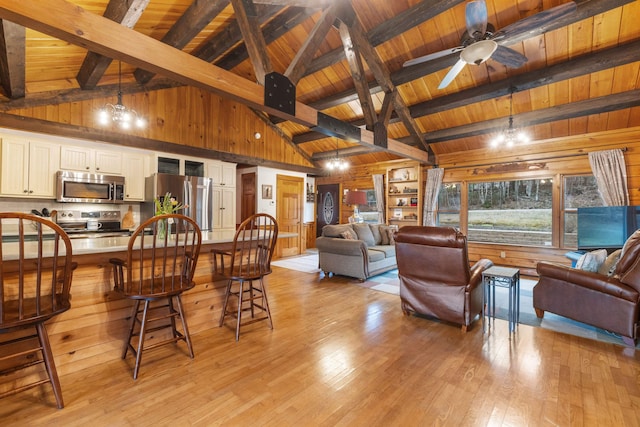 living area with wooden walls, light wood-style flooring, wooden ceiling, beam ceiling, and a ceiling fan