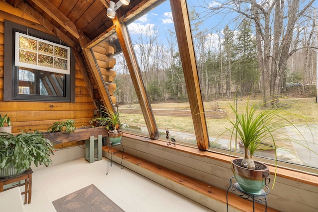 sunroom / solarium featuring wood walls, lofted ceiling, and wooden ceiling