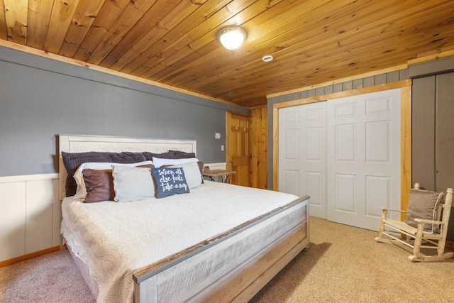 bedroom with light colored carpet, wood ceiling, a closet, and wainscoting