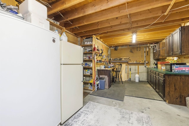 unfinished below grade area featuring a workshop area, freestanding refrigerator, and white fridge