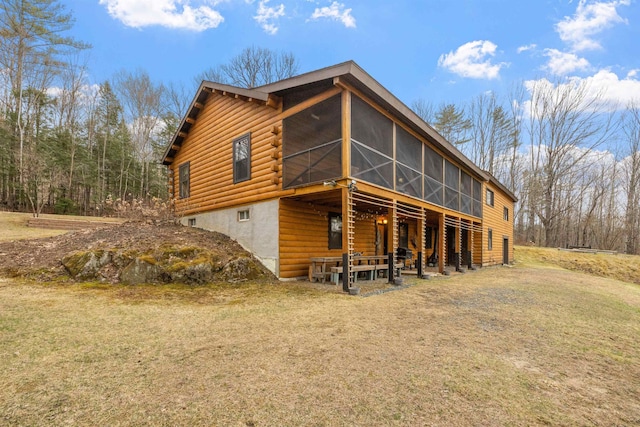back of house featuring a sunroom and a lawn