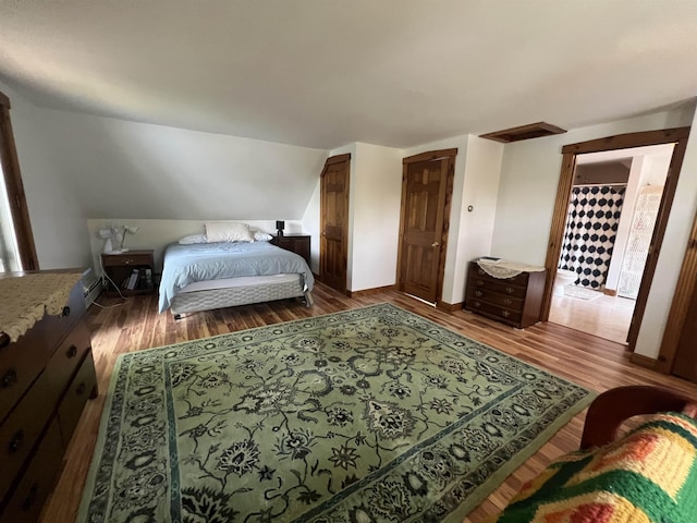 bedroom with wood finished floors, vaulted ceiling, and baseboards