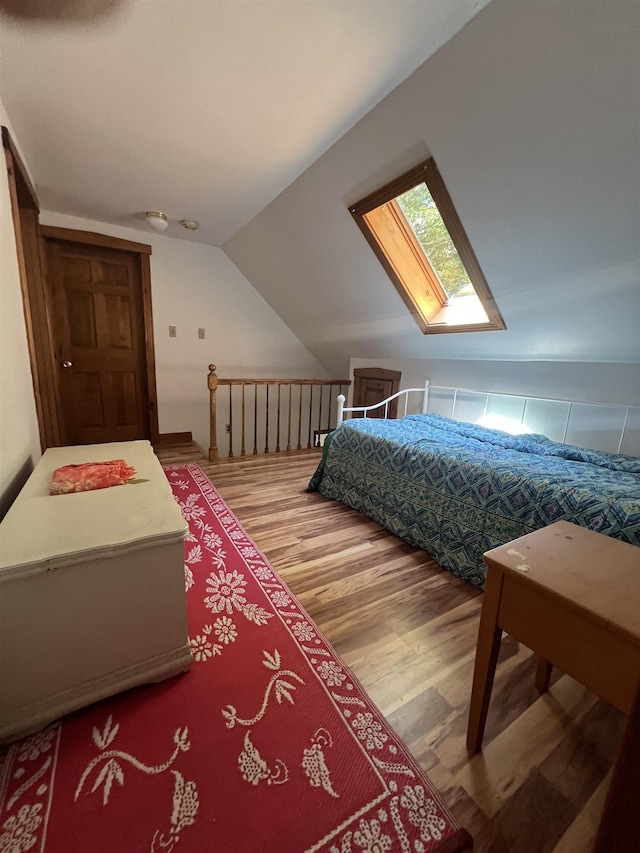 bedroom with a skylight, wood finished floors, and vaulted ceiling