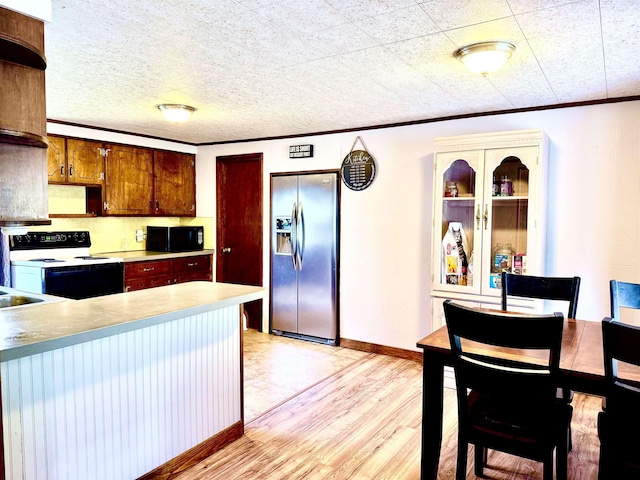 kitchen with stainless steel fridge, black microwave, electric stove, light wood-type flooring, and crown molding