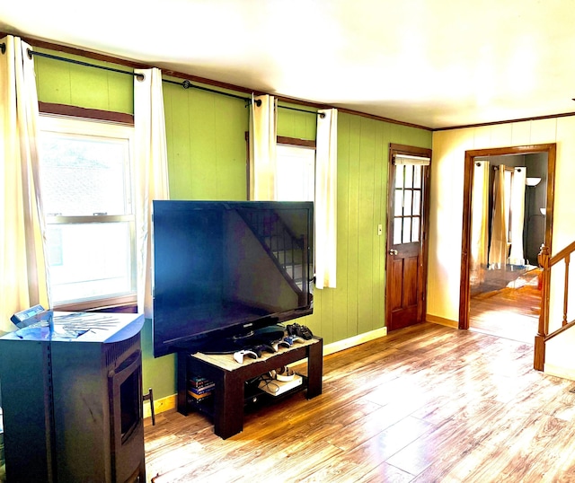 living area featuring baseboards, crown molding, and wood finished floors