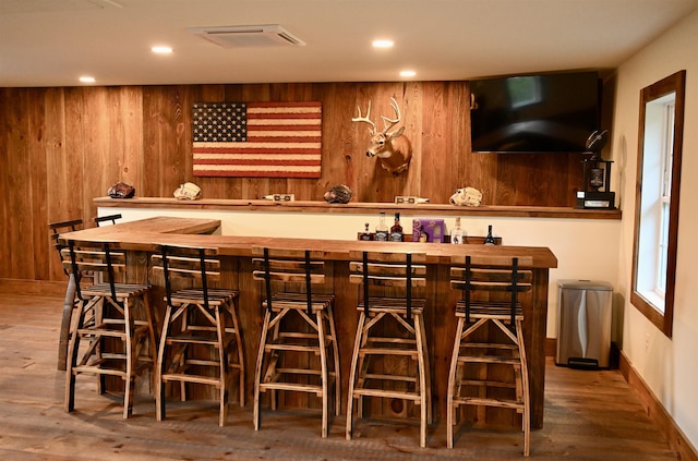indoor wet bar featuring wood finished floors, recessed lighting, wood walls, and baseboards