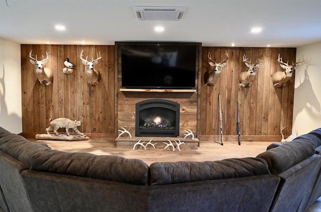 living area featuring wood walls, recessed lighting, wood finished floors, a fireplace, and baseboards