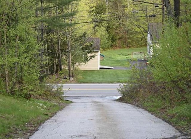 view of asphalt street with a wooded view