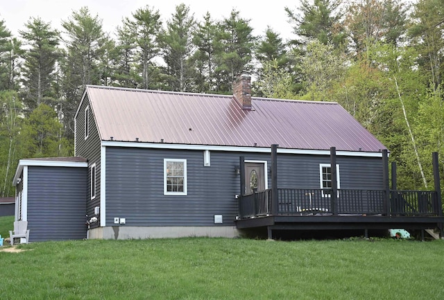 back of house featuring a wooden deck, a yard, a chimney, and metal roof