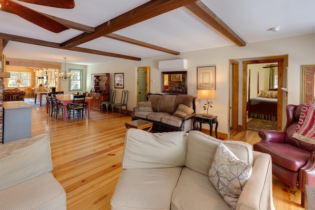 406 Partridge Lake Rd, Littleton, NH 03561 - living room with an AC wall unit, a chandelier, light wood-type flooring, beamed ceiling, and baseboards