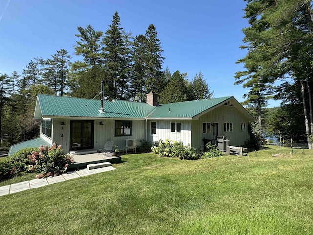 406 Partridge Lake Rd, Littleton, NH 03561 - back of house with a chimney, board and batten siding, a lawn, and metal roof