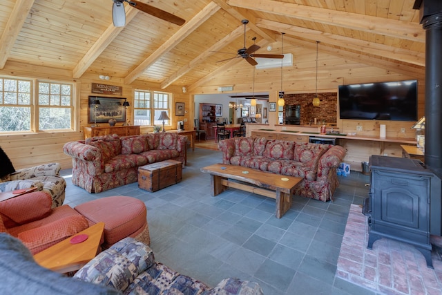 406 Partridge Lake Rd, Littleton, NH 03561 - living area featuring a wood stove, a ceiling fan, wooden ceiling, wood walls, and beamed ceiling