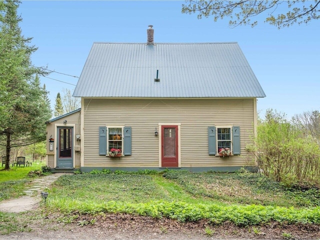 rear view of property featuring metal roof and a chimney