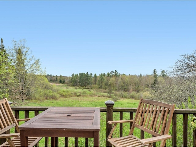 wooden terrace featuring a lawn and a view of trees
