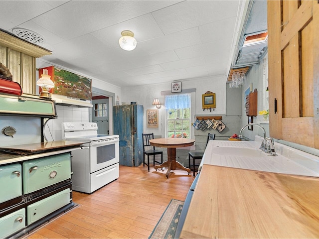 kitchen featuring electric stove, a sink, light wood-style flooring, and light countertops