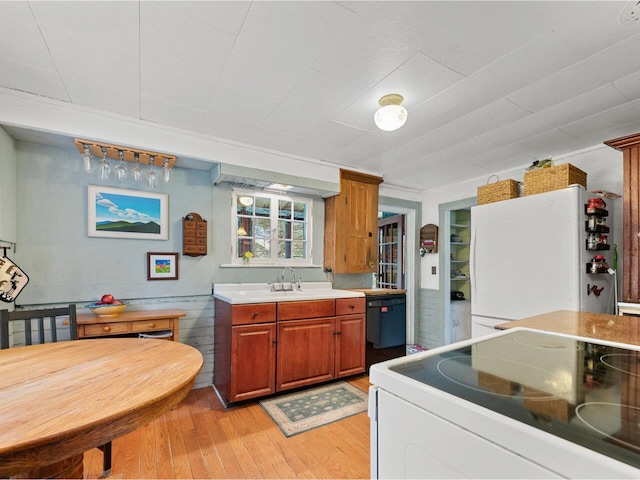 kitchen with white appliances, light wood-style flooring, light countertops, brown cabinets, and a sink