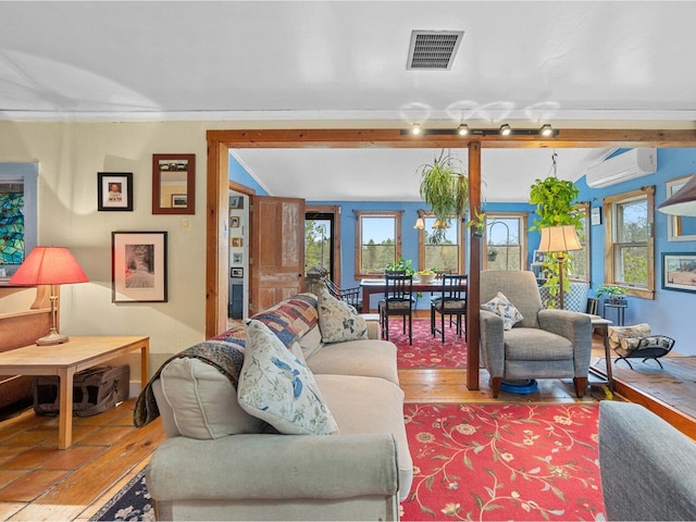 living area featuring healthy amount of natural light, an AC wall unit, wood finished floors, and ornamental molding