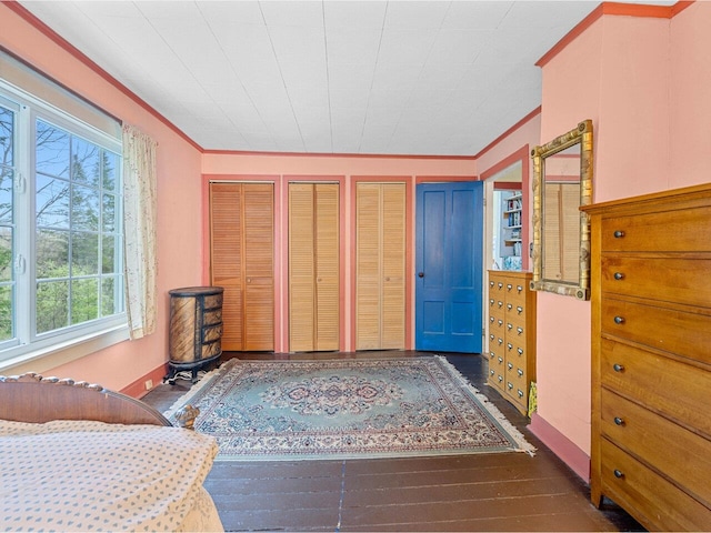 bedroom with two closets, wood finished floors, and crown molding