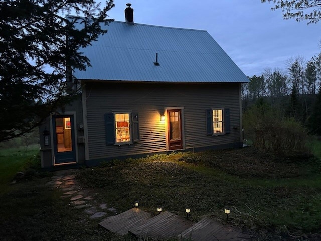 rear view of property featuring a chimney and metal roof