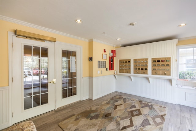 doorway to outside with wood finished floors, wainscoting, ornamental molding, french doors, and a decorative wall