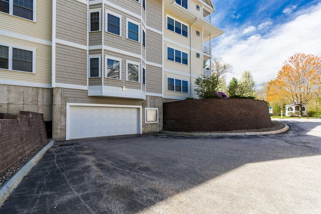 view of property featuring an attached garage and asphalt driveway