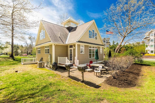 rear view of property featuring roof with shingles, a yard, a patio area, a wooden deck, and central AC unit